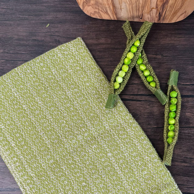 Lime Green and white honeycomb design dish towel - hand woven hemp and cotton blend. Pictured on a brown table with snap peas and a wooden cutting board.