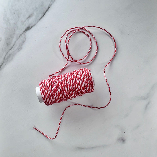 Red and white spiral hemp cord partially unwound on a white marble table.