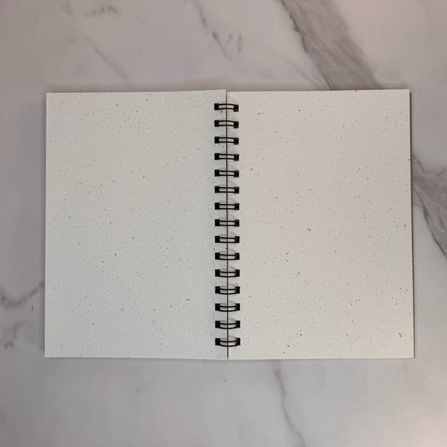 Open book view of hemp paper sketchbook with unlined paper. Spiral wire binding can be seen between left and right pages.