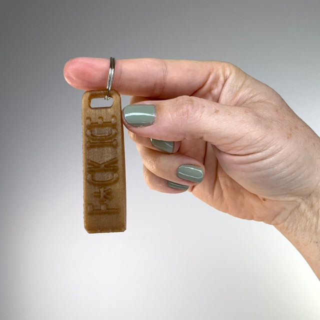 Hand holding a keychain with text against a gray background