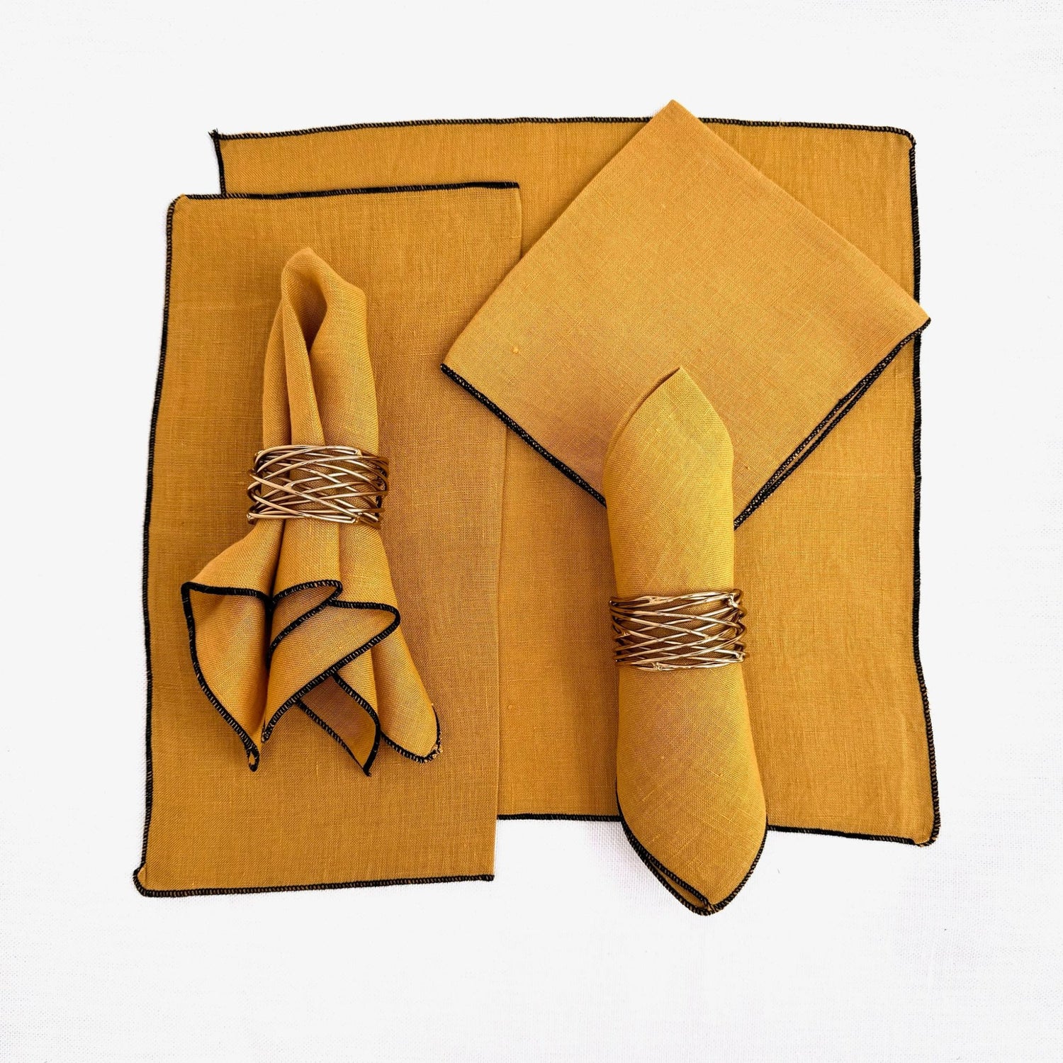 100% hemp mustard color table napkin pictured with 5 different ways to fold the napkin.  Napkins have black threading on the edge.