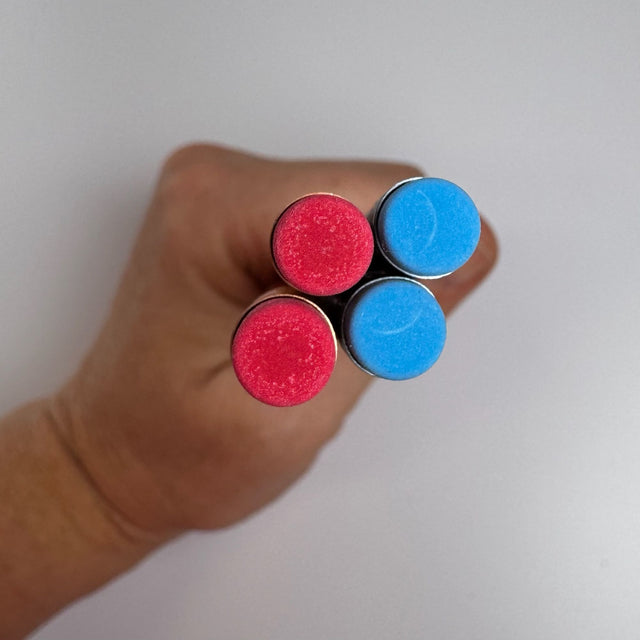 top view of 4 pencil erasers - two are blue and two are red. Held in a hand with a white background