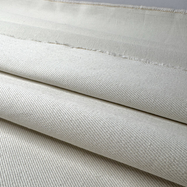 Close-up of cream fabric with a subtle pattern and edges shown