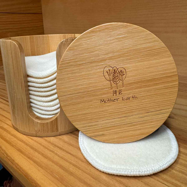 Cylindrical Bamboo box with hemp facial rounds stacked inside. Box has a slit opening down the side for dispensing. Lid is off the box and shown so you can read the top of the box "me mother earth"