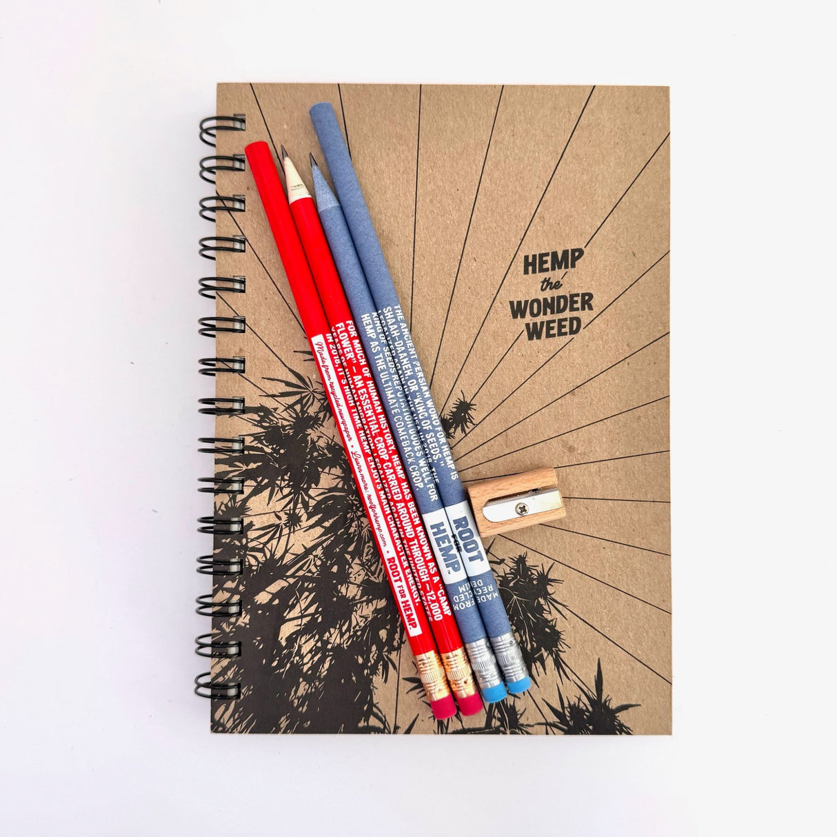 Sketchbook with "Hemp the Wonder Weed" design and blue and red pencils and sharpener
