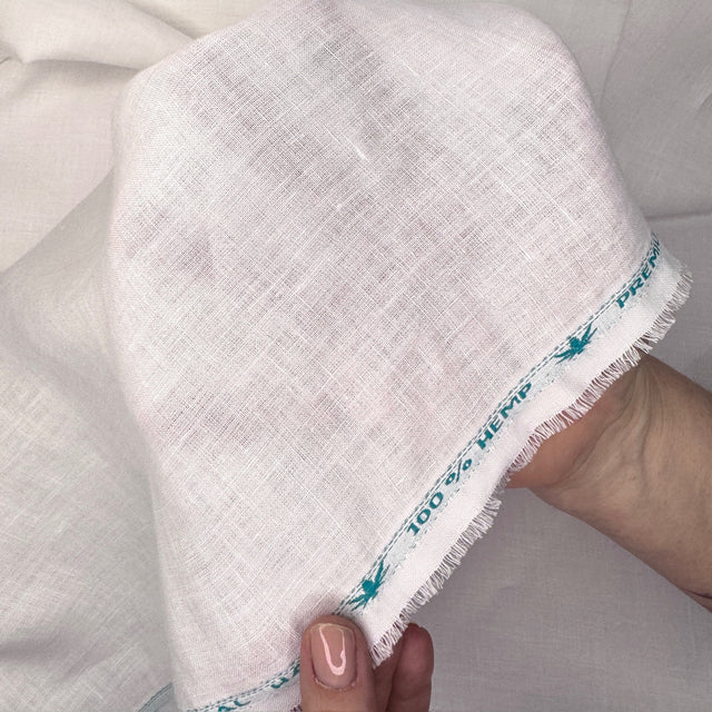 White fabric with blue text held by a hand against a neutral background