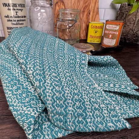 Dark Teal and white honeycomb design dish towel - hand woven hemp and cotton blend.  Pictured on a brown table, with a plant, two antique cans, and two mason jars in the background.. 