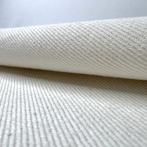 Close-up of textured cream fabric with a slight roll on a light gray background