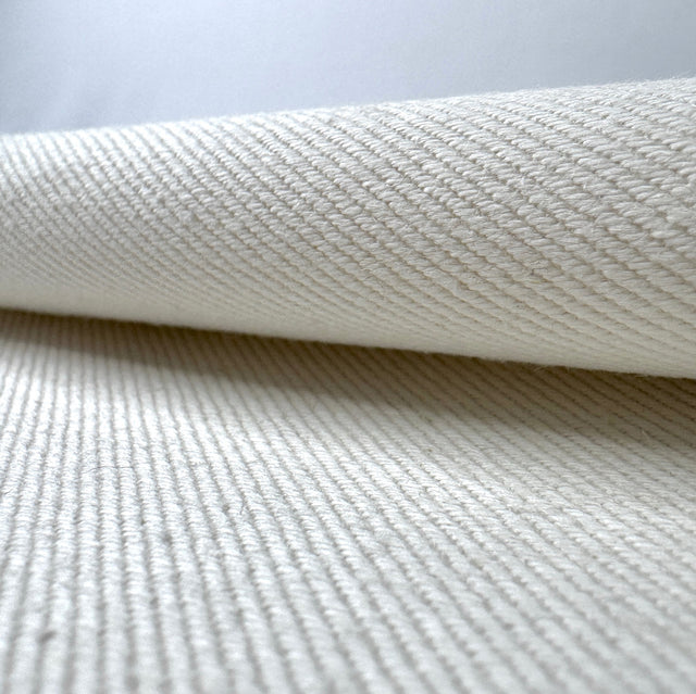 Close-up of textured cream fabric with a slight roll on a light gray background