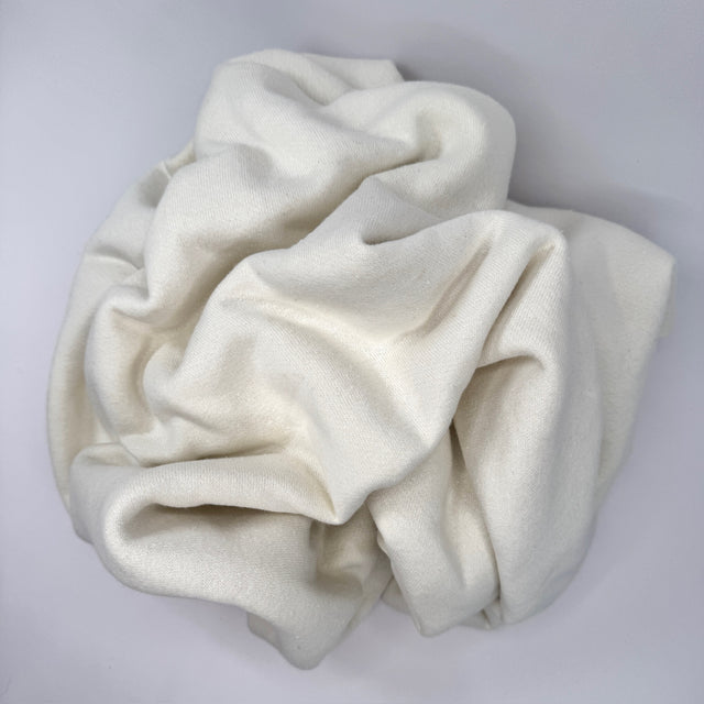 Scrunched ball of  cream fleece fabric on a light gray background