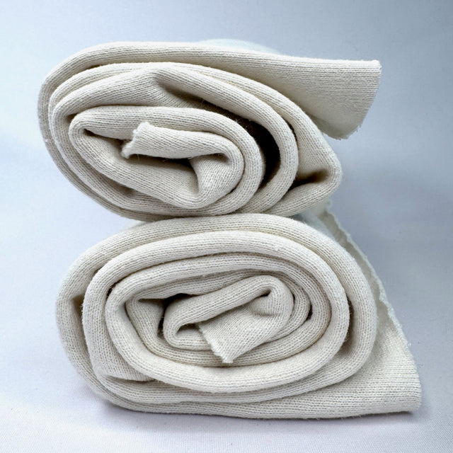 Two folded cream sweatshirt fabric on a light gray background