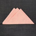 pink triangular folded pocket sqare on a black textured surface