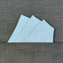 light blue pocket square on a dark gray textured surface