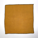 Mustard yellow fabric square with black trim on a white background
