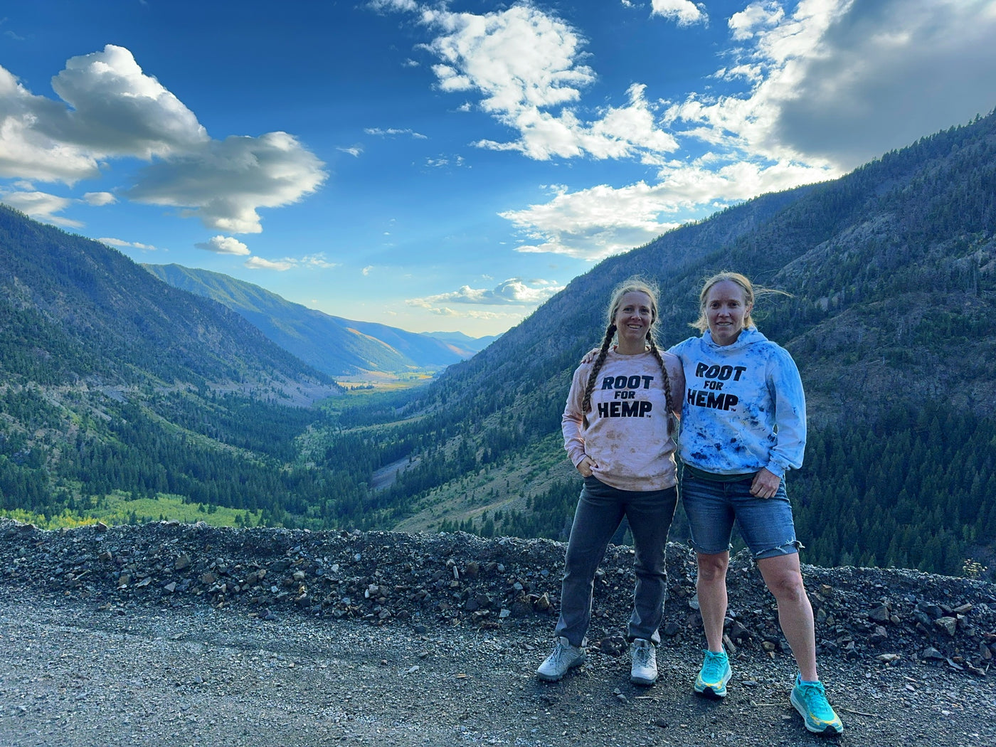 Lauren Gibbs and Stacy Lissandrello standing on the edge of a dirt trail with a green valley view in the background