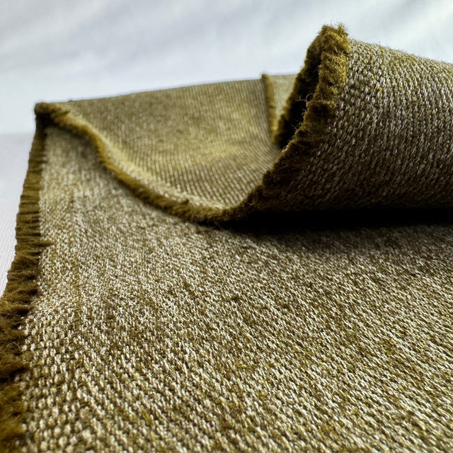Close-up of a textured olive hemp twill fabric with frayed edges on a white background