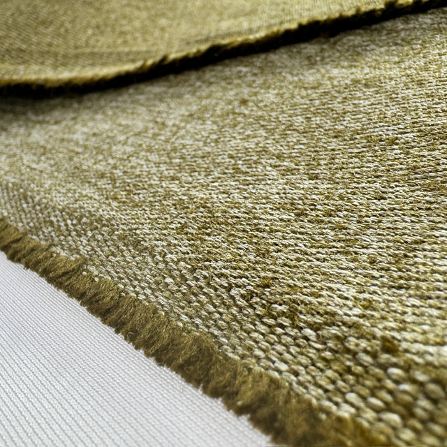 Close-up of a textured olive green hemp twill fabric with frayed edge on a white background