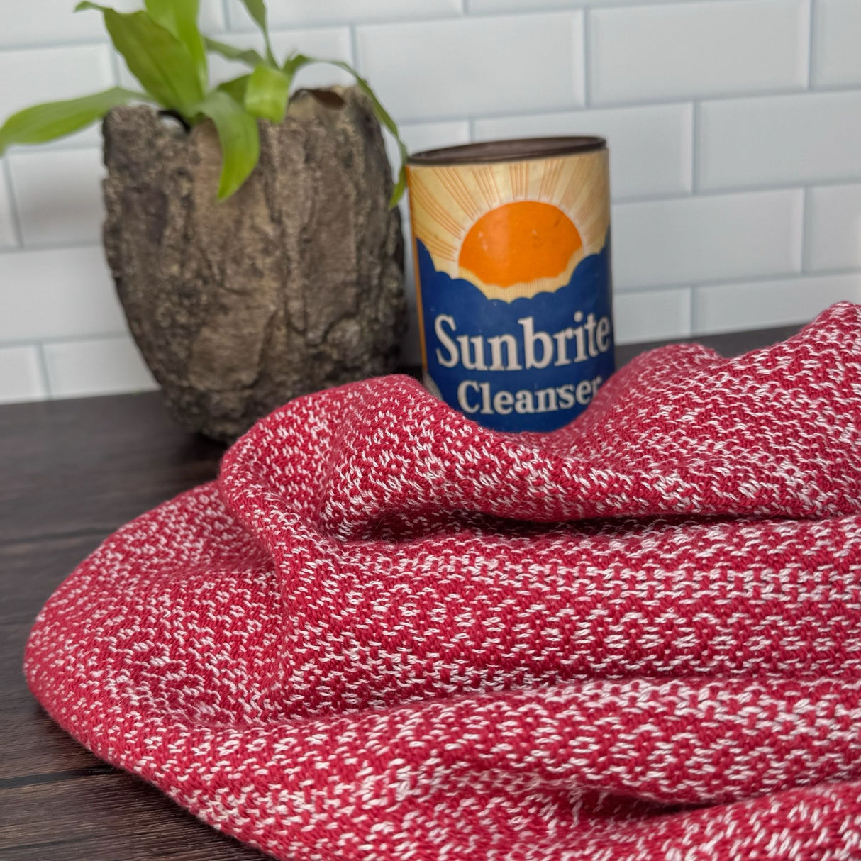 Red and white honeycomb design dish towels - hand woven hemp and cotton blend.  Pictured on a brown table, with a plant and antique can in the background.