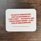 Back is white with the following message printed in red:  “For much of human history, hemp has been known as a “camp flower” - an essential crop carried around through ~12,000 years of human migration.”  and "learn more at rootforhemp.com"