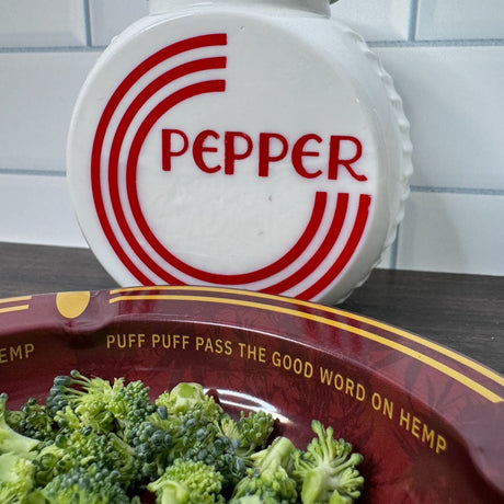 Closeup view of the inside rim of the ash tray to show the words "puff puff pass the good word on hemp'.  A vintage red and white pepper shaker is in the background.