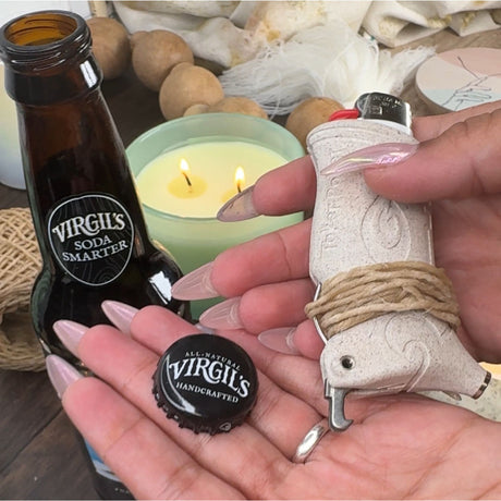 Grey toker poker with bottle cap opening flipped open.  Shown with an open bottle and candles int he background. 