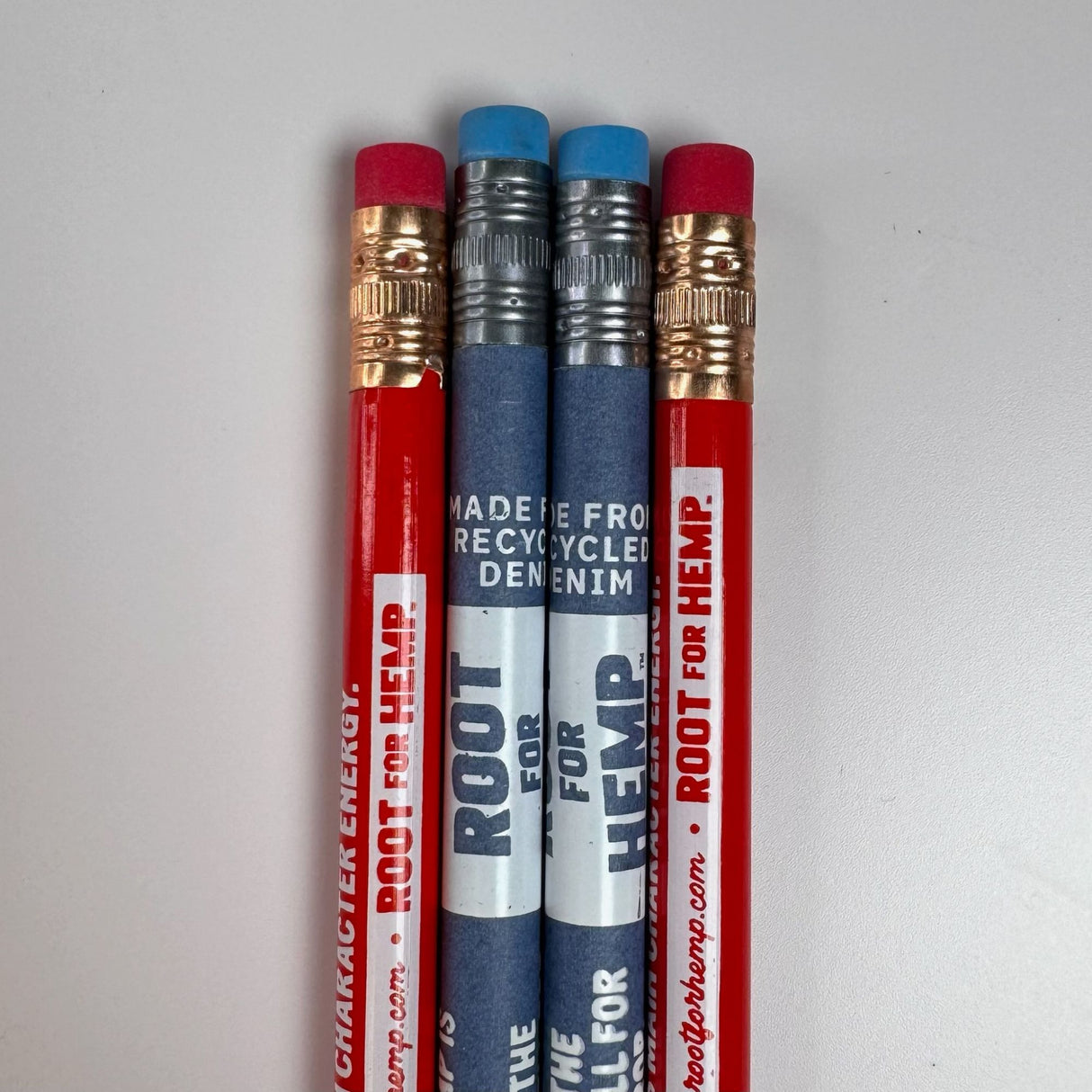 The eraser end of four pencils is pictured.  Two red pencils with red erasers, gold metal attaching erasers to pencils and white hemp messaging printed on pencil.  two blue pencils with blue erasers, silver metal attaching eraser to the pencils, white hemp education message printed on the pencil in white font.