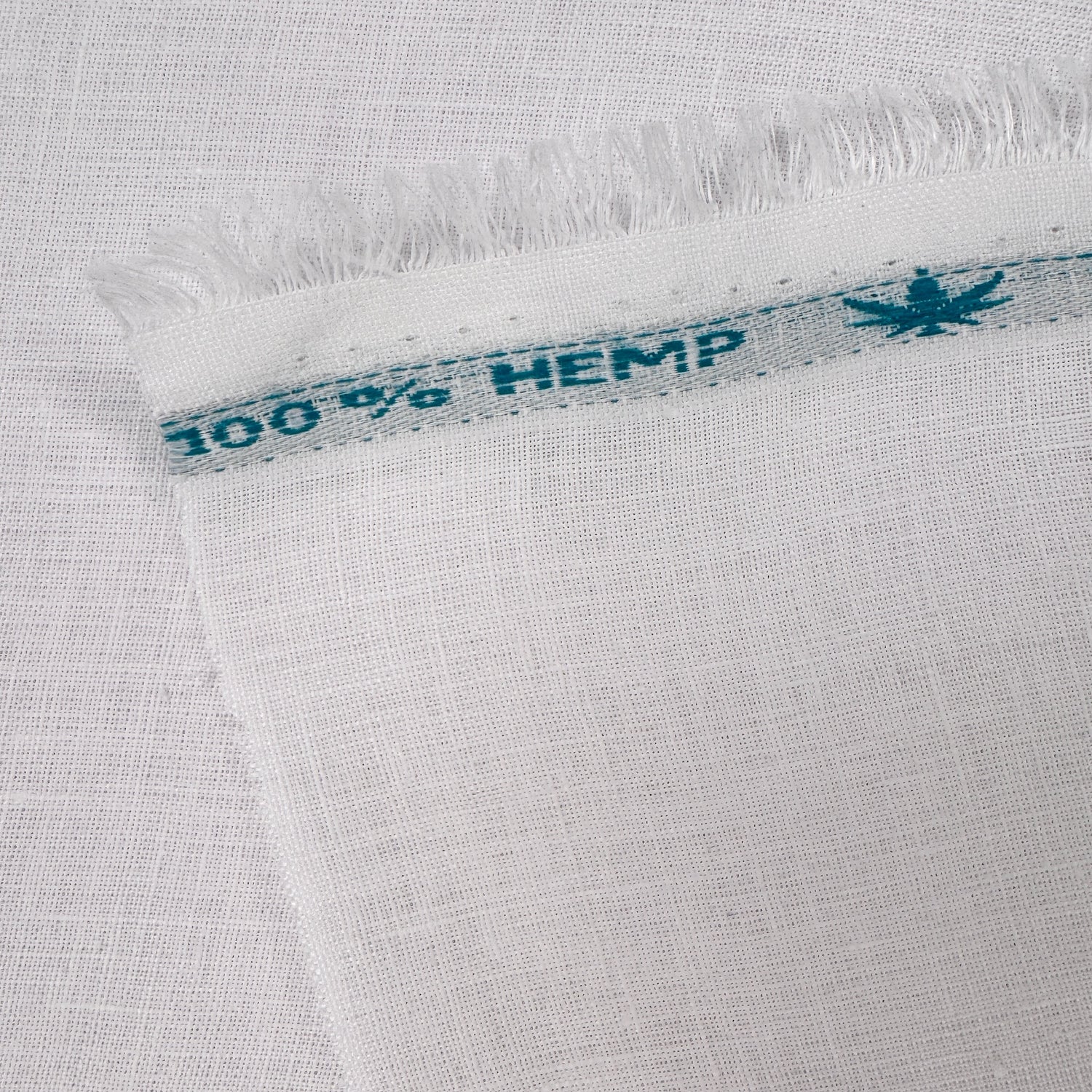 Close-up of white fabric with a '100% Hemp' label.