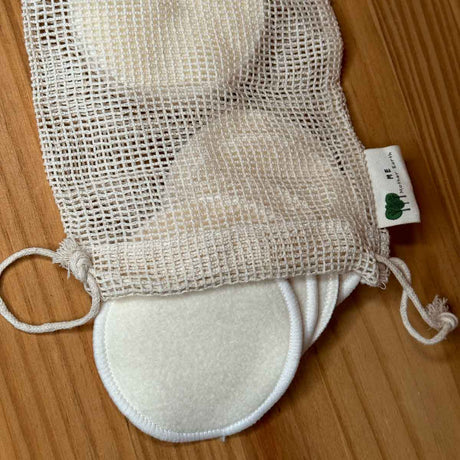 Mesh washing bag with hemp facial rounds inside, not fully loaded. Bag has strings at the top for securing. 