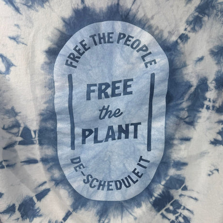 Closeup view of the printing on the back of the hoodies - "Free the People, Free the Plant, DE-Schedule it" surrounded in indigo tie-dye design.