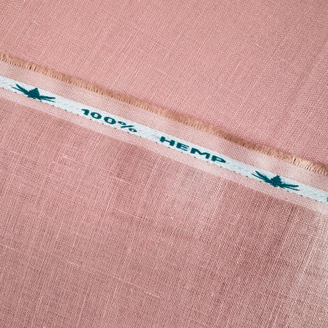Close-up of pink fabric with a white stripe displaying '100% Hemp' text.