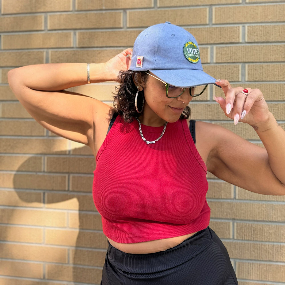 Model wearing the hemp vote hat - angled front-side view showcasing the joint/pencil holder.  Model is wearing a red tank top black bottoms, and green glasses.