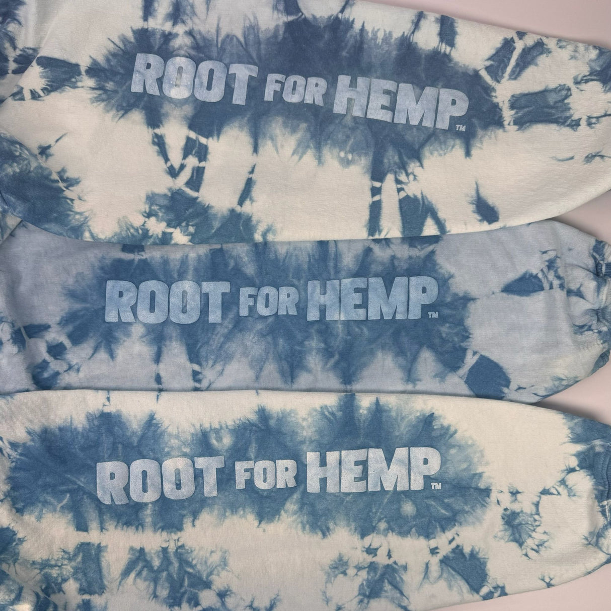 Closeup view of the printing on the left arm of the hoodies - "Root for Hemp" surrounded in indigo tie-dye design. Picture shows the uniqueness of the dye pattern on each unit. 