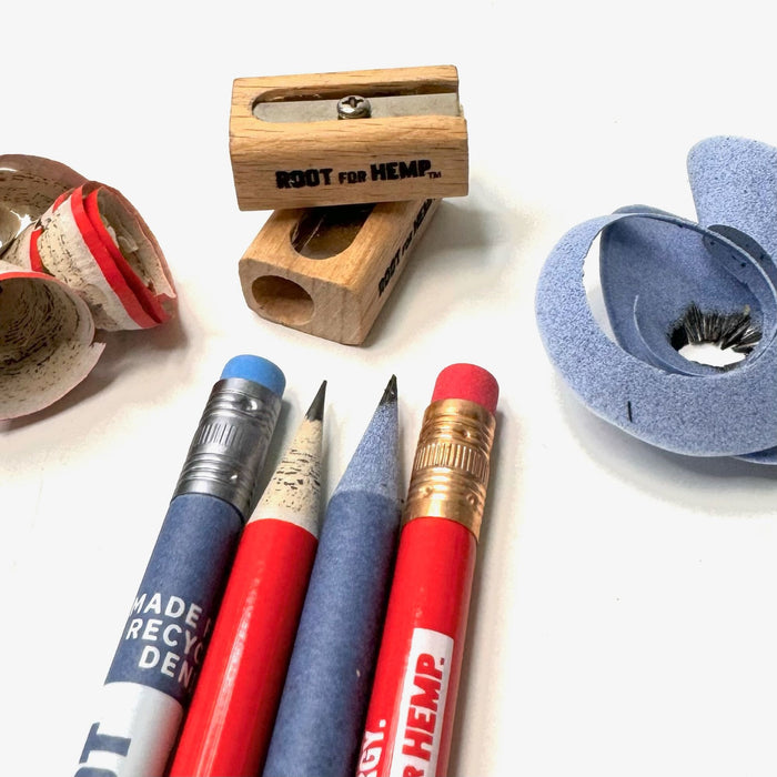 Four pencils )two red and two blue) - two showing the tip and two showing the eraser. Pictured with two root for hemp branded wooden pencil sharpeners and the red and blue shavings from sharpening the pencil.